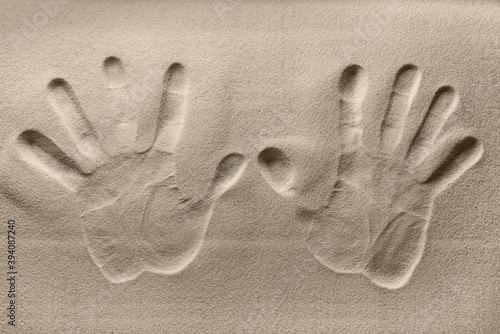 The texture of a sandy surface with the imprint of the left and right hands of a person