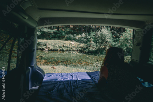 Woman views from the mattress of the van to the river
