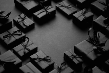 Arranged Gifts boxes wrapped in black paper with black ribbon on black background. Christmas concept