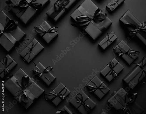 Arranged Gifts boxes wrapped in black paper with black ribbon on black background. Christmas concept