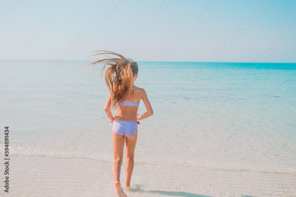 Naklejka premium Adorable active little girl at beach during summer vacation