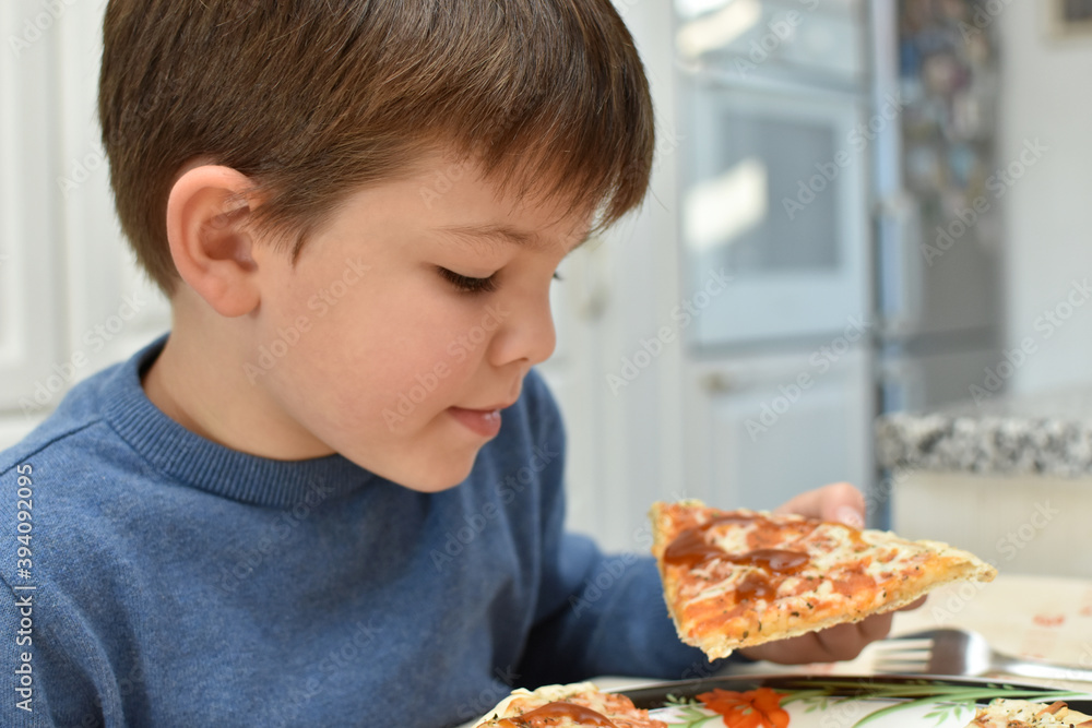 Happy boy eats pizza. Child eating pizza, ordering fast food for dinner