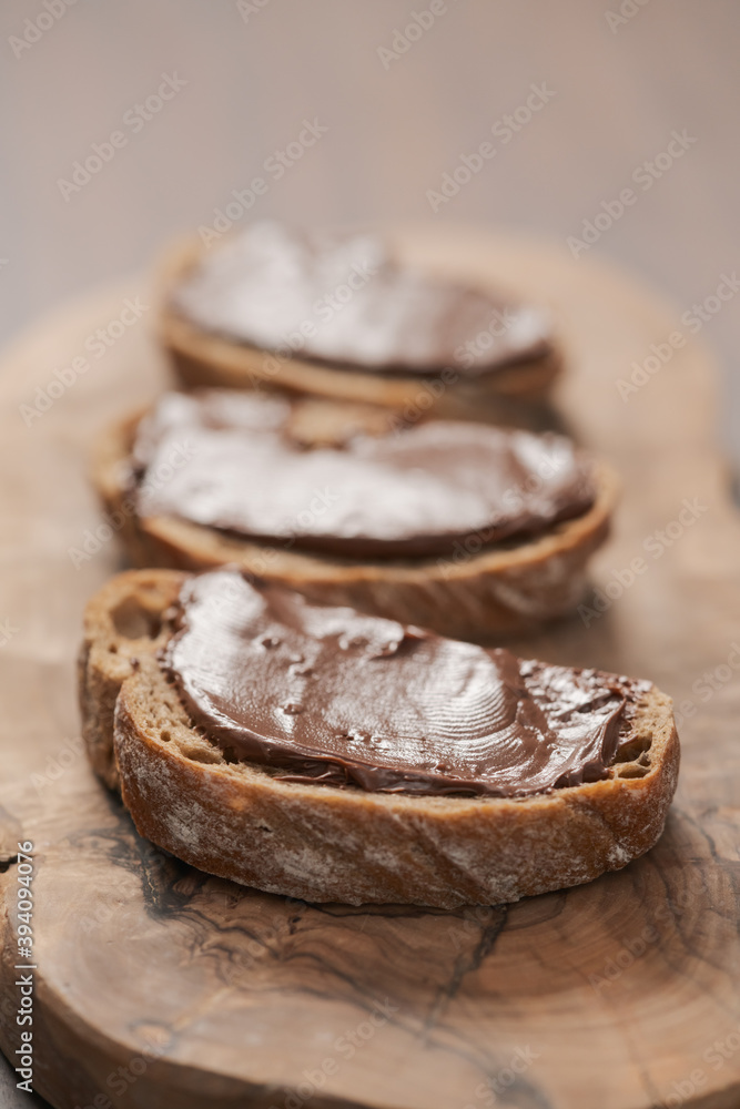 Ciabatta slices with chocolate spread on olive wood board Ciabatta slices with chocolate spread on olive wood board