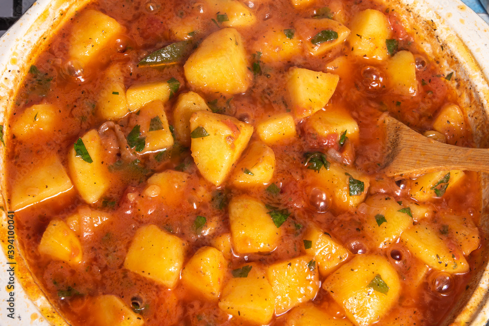 Cooking Greek vegetable stew of potatoes and vegetables in tomato sauce in a large frying pan, top view Cooking Greek vegetable stew of potatoes and vegetables in tomato sauce in a large frying pan, top view