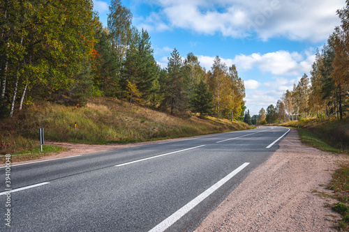 View of the highway road in the fall. Traveling background. Asphalt highway passing through the forest. Latvia. Baltic.