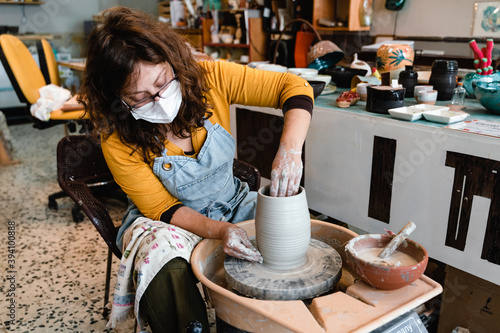 Charming pottery master making ceramic pottery on wheel. Handcraft.