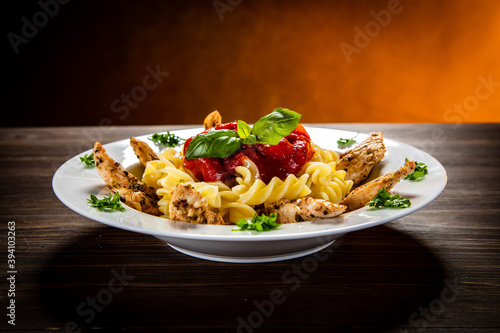 Roast chicken nuggets with fusilli and tomato sauce on wooden table