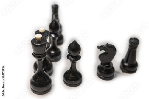 Wooden chess pieces. Black king and Queen surrounded by their large retinue, stand one behind the other, deployed in full face