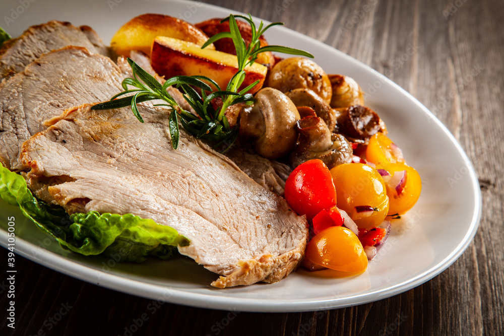 Roasted pork ham, champignons and fried potatoes on wooden table