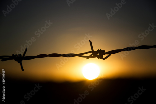 Sun at sunset with detail of a wire