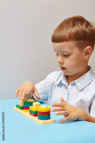 The boy is playing in his room. Learning shapes and colors. A child plays with a sorter. Educational logic toys for kid's. Montessori Games for Child Development.