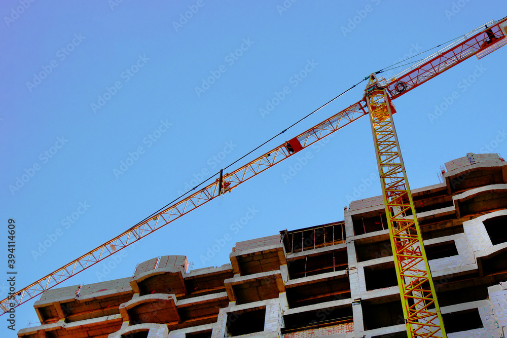 Сrane near building. Concrete building under construction.