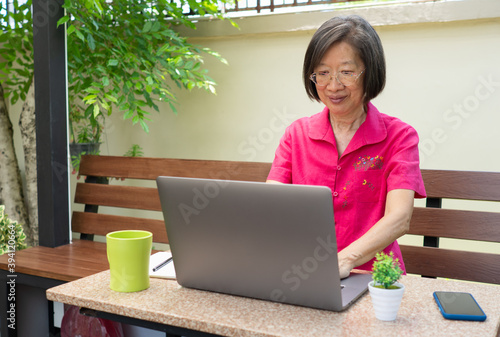 senior reitred asian woman using computer to write email and sitting at home photo