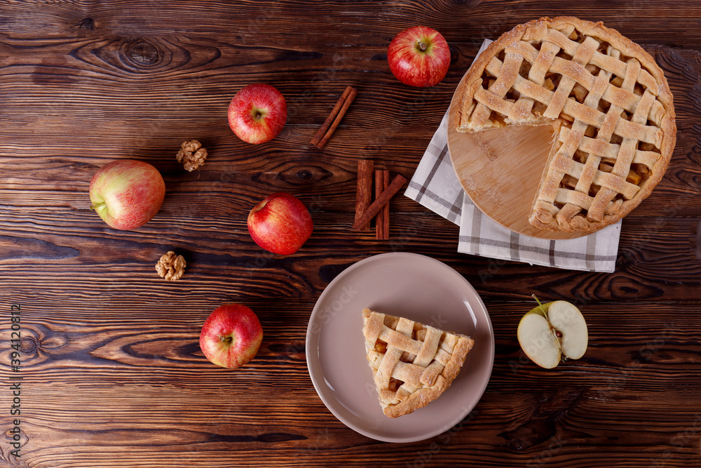 Traditional American Thanks Giving pie with whole organic apples, cinnamon sticks on wooden table. Homemade fruit tart baked to golden crust. Close up, copy space, top view, background.