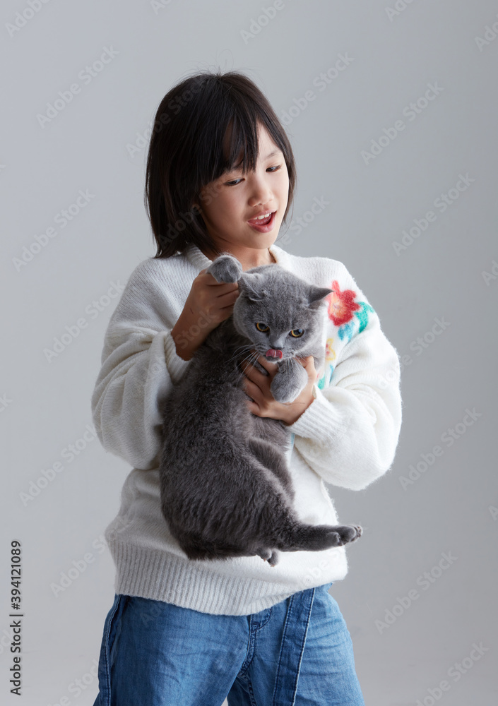 Cute asian little girl playing with cute pet cat, indoors