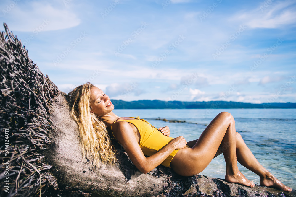 Young blonde lying on dead tree on beach Young blonde lying on dead tree on beach