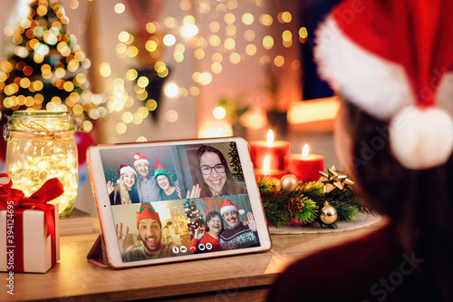 Young woman having a Christmas video call with her happy family. Concept of families in quarantine during Christmas because of the coronavirus. Xmas still life with a tablet in a cozy room