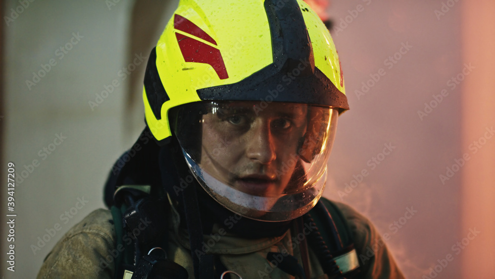 Potrait of young firefighter in full uniform in front of burning house. High quality photo Potrait of young firefighter in full uniform in front of burning house. High quality photo