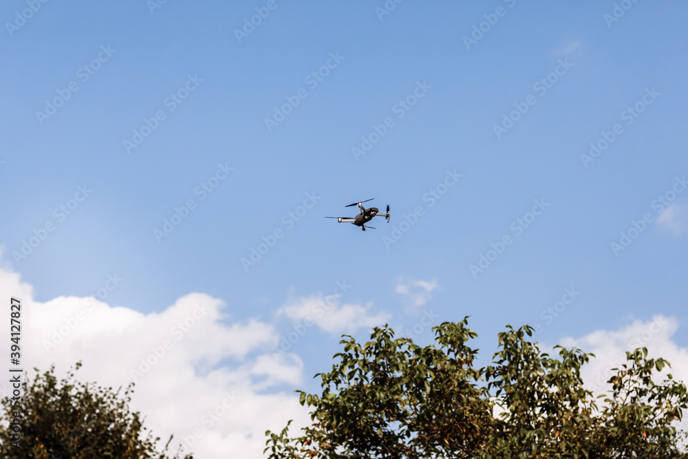 Quadcopter drone in sky. Small drone flies in sky over the park taking video and photos. Remote control air delivery and spy. selective focus. Quadcopter drone in sky. Small drone flies in sky over the park taking video and photos. Remote control air delivery and spy. selective focus.