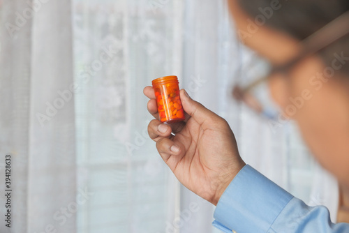 rear view of man holding pill container on blue background  photo