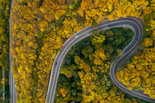 Smountain road along the sea, aerial vieweaside resort, Serpentine, aerial view of road along seaside of island with forest autumn on hill side back ground. © evgenii