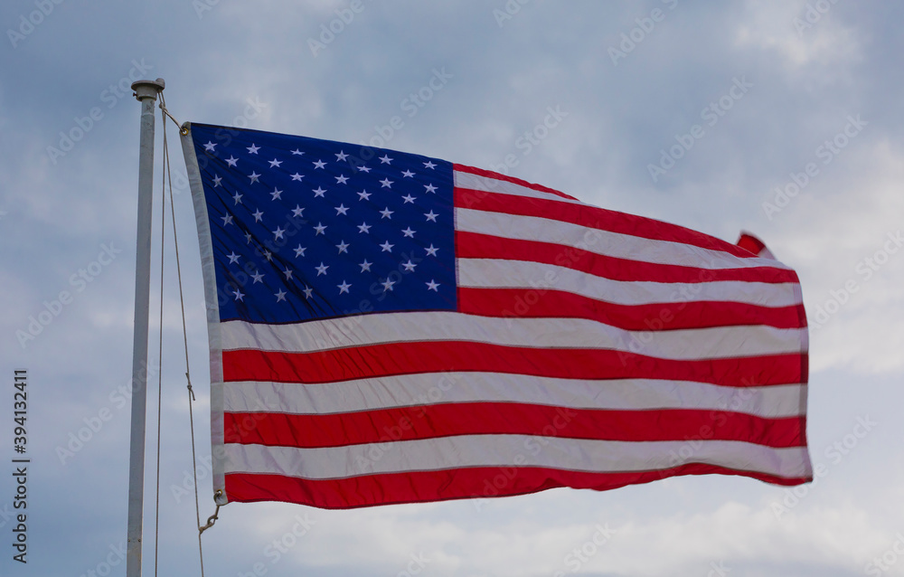 Obraz premium Stars and stripes flying with sky behind