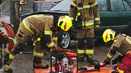 Firefighters preparing the hose for hidraulic cutter on the car crash scene. High quality photo