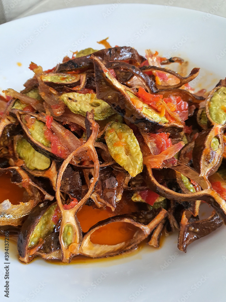 Close up of deep fried anchovies and bitter beans stir fried with chili paste (sambal petai ikan teri). Popular Indonesian and Malaysian traditional cuisine. Spicy, rich flavor and delicious. Isolated Close up of deep fried anchovies and bitter beans stir fried with chili paste (sambal petai ikan teri). Popular Indonesian and Malaysian traditional cuisine. Spicy, rich flavor and delicious. Isolated