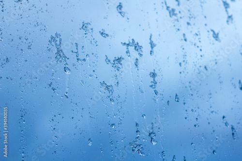abstract background, streams of rain and snow on the glass on the background against the blue of a stormy sky