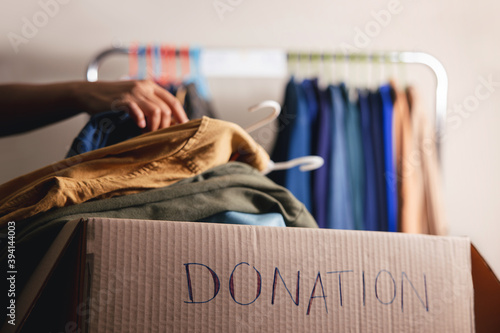 Donation Concept. Preparing Used Old Clothes from Wardrobe Rack into a Donate Box. Focus on Text