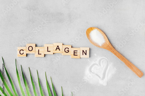 collagen powder in a spoon on a gray table, top view, green leaf, heart, inscription collagen
