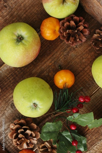 Green apples tangerines and pine cones on the table