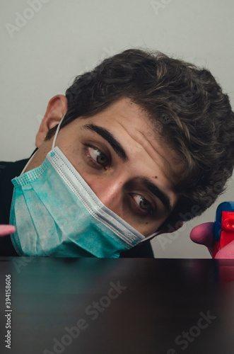 hombre joven con mascarilla guantes y desinfectante limpiando