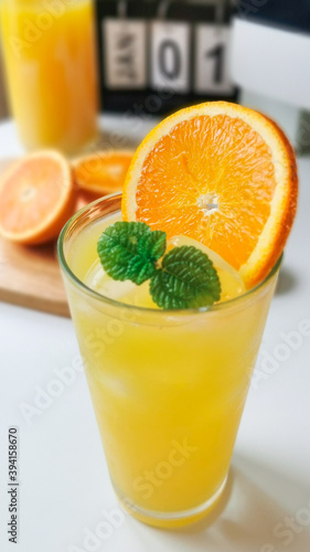 Yellow orange juice and ice on white table, refreshment drink cold beverage for hot days.