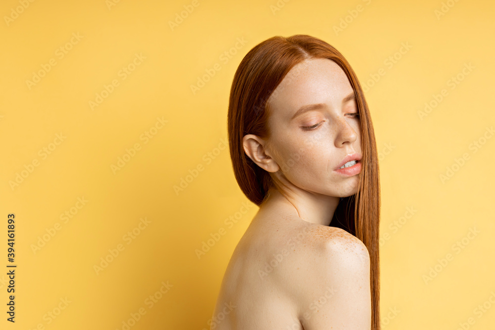 Beauty, spa and care concept. Close up side view portrait of graceful sensual naked redhead lady with clean skin looking down isolated on yellow background with copy space. Beauty, spa and care concept. Close up side view portrait of graceful sensual naked redhead lady with clean skin looking down isolated on yellow background with copy space.