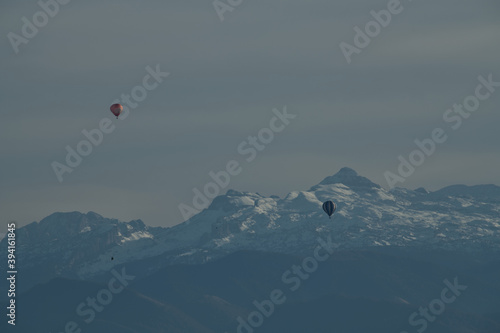 Magnifique paysage de montagne avec ses Pyrénées enneigées en toile de fond et ces deux montgolfières qui survolent la plaine des Pyrénées Atlantique par un beau jour d'automne