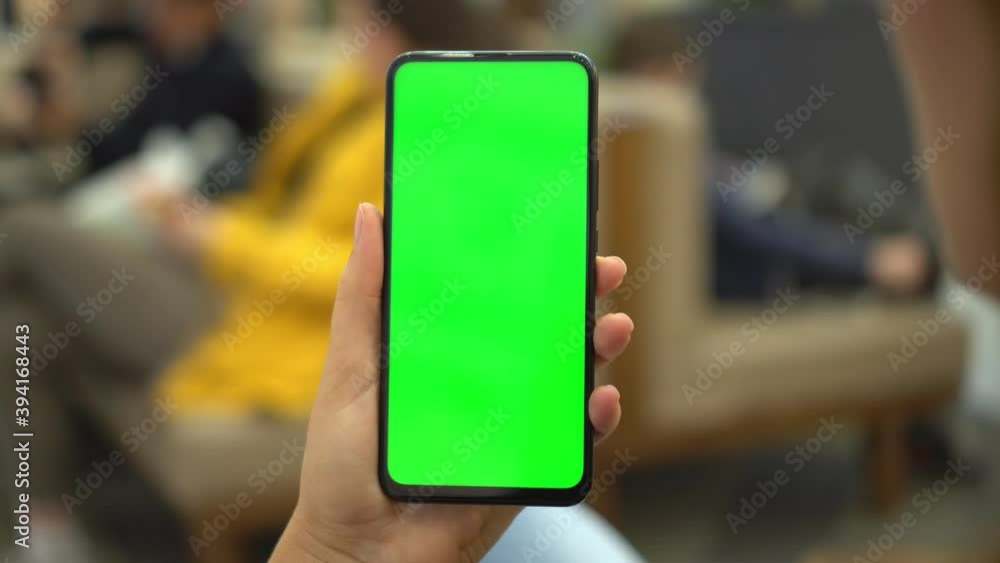 Shopping center. Department store. Mall. Back view of brunette holding chroma key green screen smartphone watching content. Shopping online. Gadgets and contemporary people concept. Shopping center. Department store. Mall. Back view of brunette holding chroma key green screen smartphone watching content. Shopping online. Gadgets and contemporary people concept.