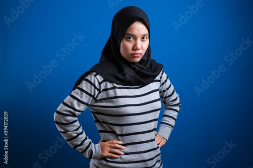 Portrait of angry cynical Asian muslim woman with suspicious expression looking at camera, mistrust misdoubt concept photo