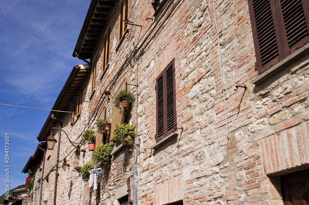 A medieval stone house in an italian village with wooden windows, plants and flowers (Gubbio, Italy, Europe)