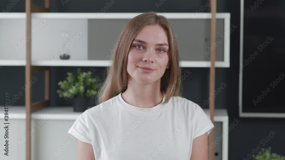 Smiling attractive young woman looking at camera at home office, happy beautiful female professional with pretty face smile posing indoors. Smiling attractive young woman looking at camera at home office, happy beautiful female professional with pretty face smile posing indoors.
