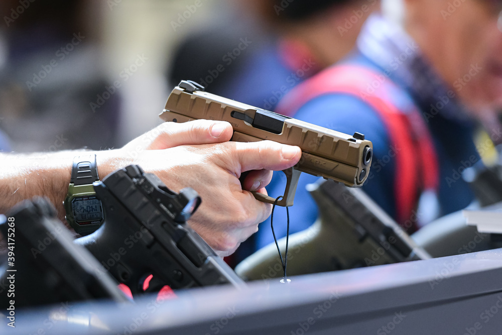 Fototapeta premium Vicenza, Italy - February 8, 2020: A man tries the Beretta APX, a striker-fired semi-automatic pistol, on display at Hit Show 2020, trade fair show dedicated to hunting, target sports and outdoor
