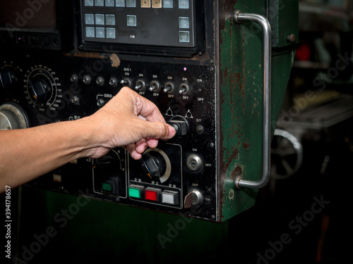 Factory worker hand turning start switch key of Control machine equipment in a metal factory.