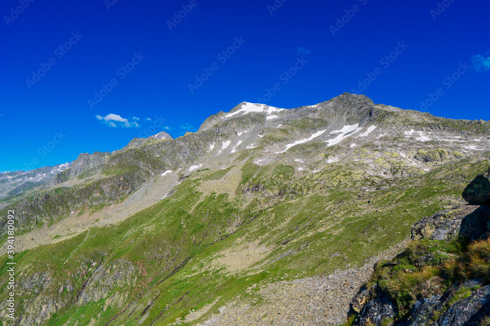 Landscape mountain view peaks in snow and green hills, deep blue sky and huge white clouds background, Hohe Tauern Austrian Alps, Europe