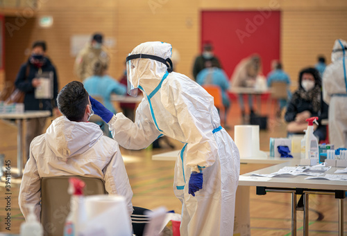 Massive rapid COVID-19 testing for the popolation. Health workers in protective suits are engaged in salivary and nasal tests inside a public gym. People get tested against the Coronavirus.