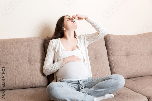 Sick pregnant woman blowing nose into tissue at home Healthy millennial healthcare concept