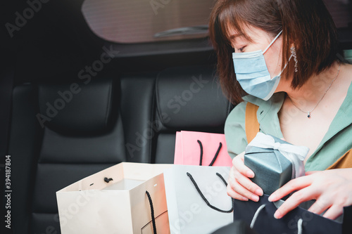 asian woman shopping and prepare new year gift in her car and wear protective mask