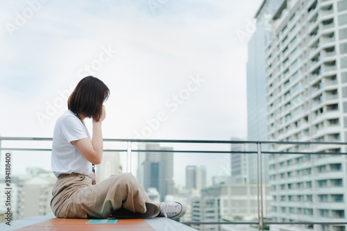 solo asian woman wear protective mask during outdoor break and relax at rooftop with city background