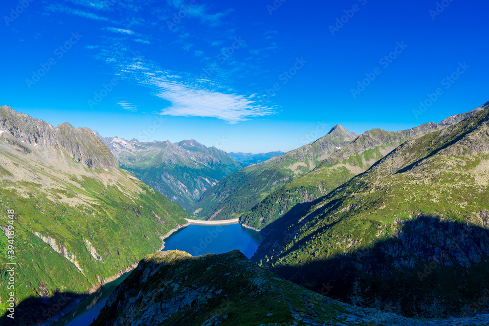 Morning mountain dawn in the Alps surrounded by summer green in the background high Alps, cloud sky. Reflections mountains in the water Zillergrundl austria zillertaler alps