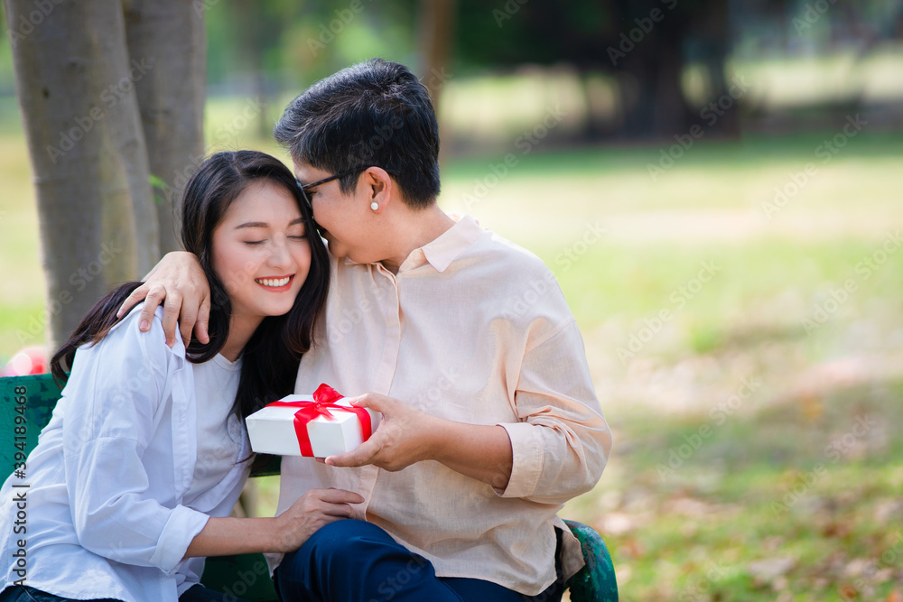 Φωτογραφία Asian mother gives warm hug and kiss to her lovely daughter after take the present box