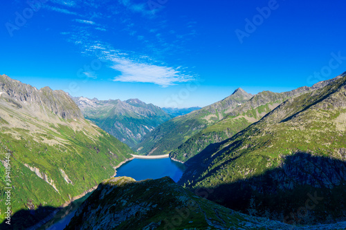 Fototapeta Naklejka Na Ścianę i Meble -  Morning mountain dawn in the Alps surrounded by summer green in the background high Alps, cloud sky. Reflections mountains in the water Zillergrundl austria zillertaler alps